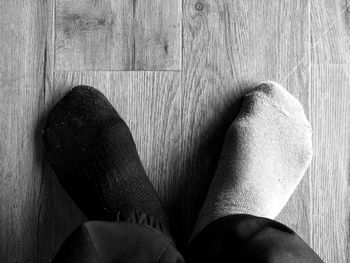 Low section of person wearing shoes on wooden floor