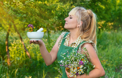 Young woman drinking water while sitting on field