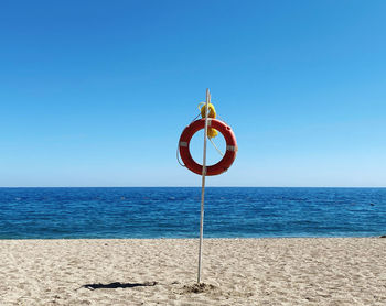 Lifeguard hut on beach against clear blue sky
