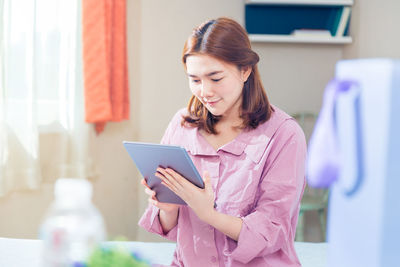 Young woman looking away while standing on mobile phone