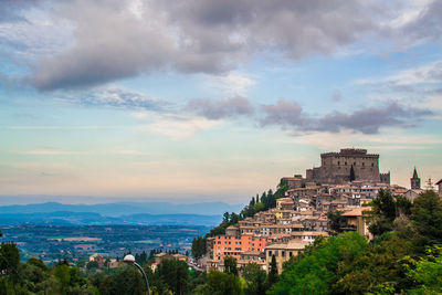 Buildings in city against cloudy sky