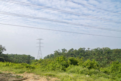 Low angle view of electricity pylon on field against sky