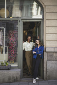 Female colleagues standing at doorway in clothing store