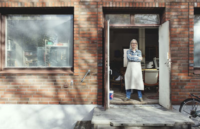 Portrait of woman standing against window