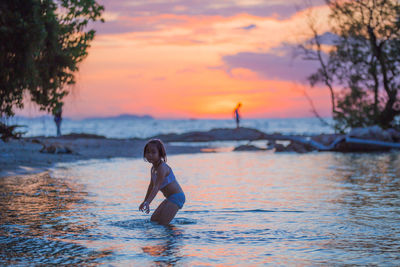 Cute girl playing in water against sea