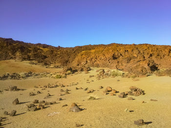 Scenic view of arid landscape against clear blue sky