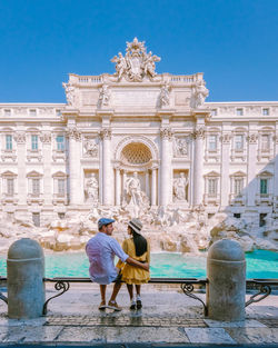 Rear view of two people in front of historical building