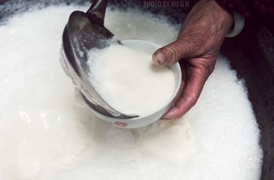 Cropped hands of man pouring sweet food in bowl