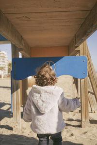 Rear view of young woman standing against wall