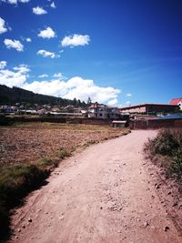 Road by landscape against blue sky