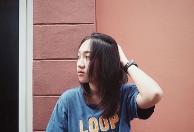 Portrait of young woman against wall