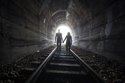 Rear view of people walking in tunnel