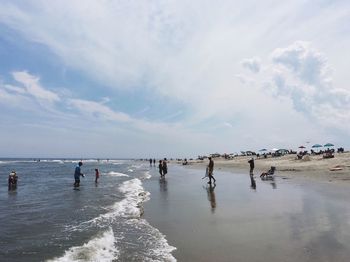 People enjoying at beach against sky