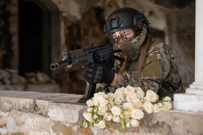 Portrait of a woman in a helmet and goggles with a machine gun in her hands. 