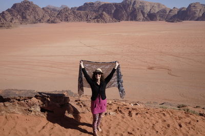 Woman with umbrella on sand dune in desert