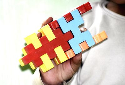 Close-up of hand holding toy against white background