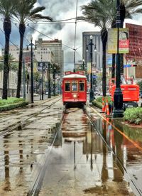 Wet road by city against sky
