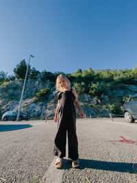 Portrait of woman standing on road against clear sky
