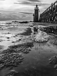 Lighthouse amidst sea and buildings against sky