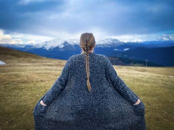 Rear view of woman standing on field against sky
