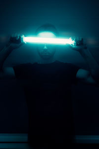 Man standing in illuminated light against black background