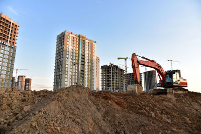 Excavator on earthmoving at construction site. road work and dig pit foundation. tower cranes 