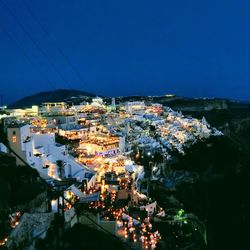 High angle view of illuminated buildings in city against clear blue sky