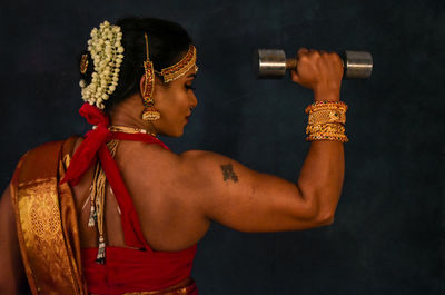 Midsection of man holding dumbbell in gym