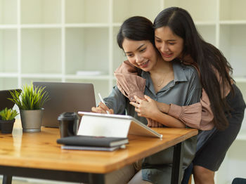 Female colleague embracing businesswoman at office