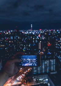 Cityscapes man shooting photos with smartphone illuminated modern buildings in city at night