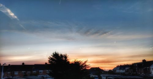 Silhouette trees and buildings against sky during sunset