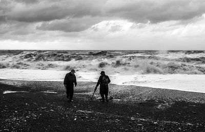 Men with metal detectors walking at beach