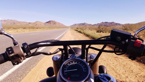 Close-up of hand on motorcycle against sky