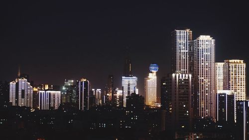 Illuminated buildings in city against sky at night