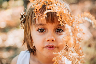 Close-up portrait of girl standing by plant outdoors