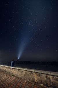 Man sitting against sky at night