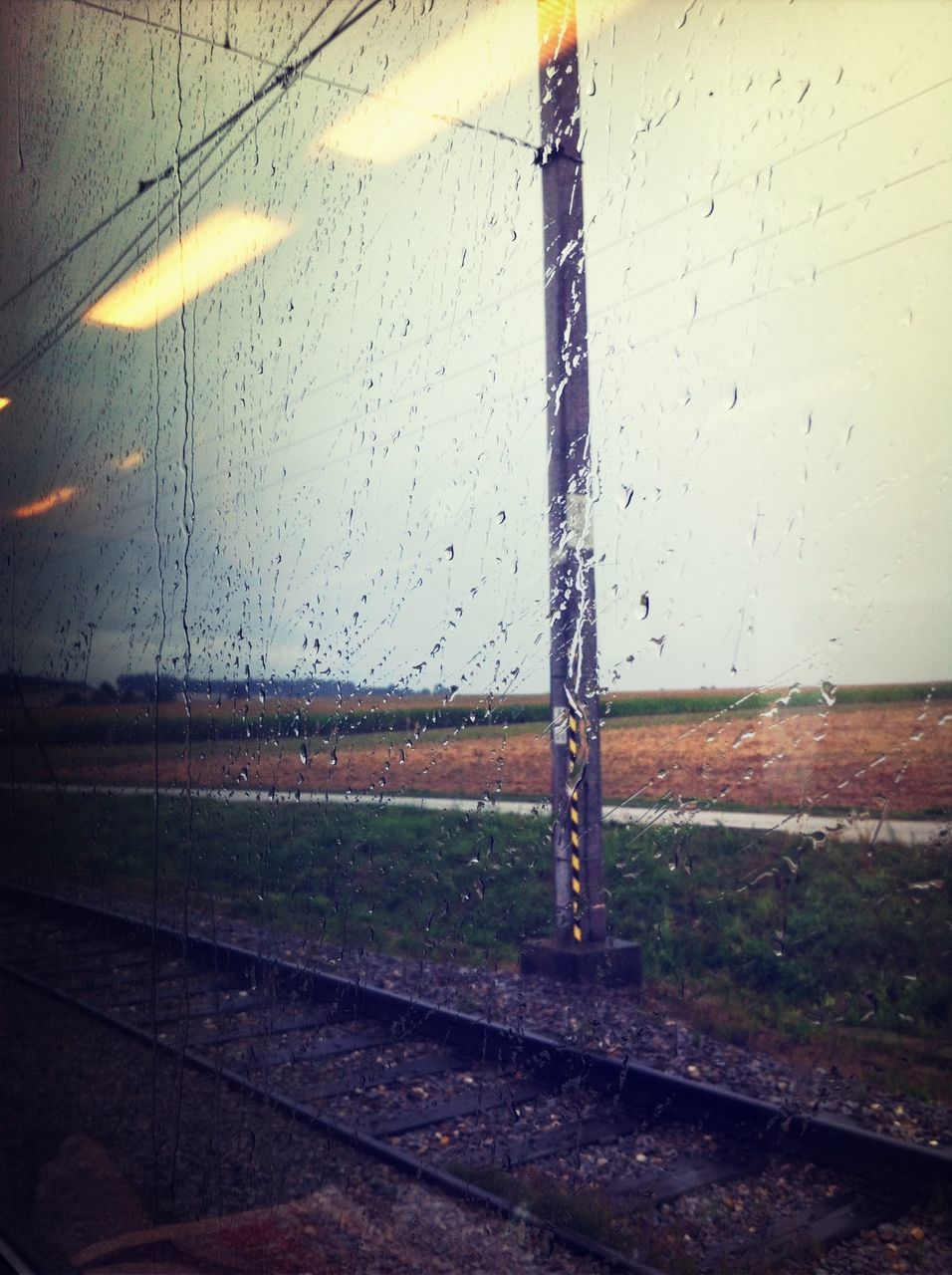 transportation, wet, sky, building exterior, built structure, road, rain, glass - material, window, architecture, street, mode of transport, weather, drop, no people, power line, electricity pylon, transparent, day, outdoors