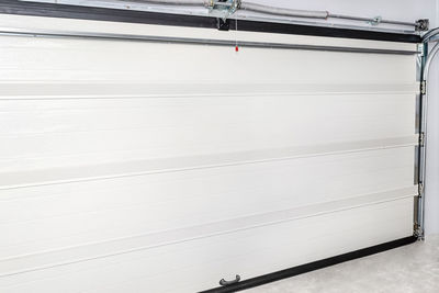 A closed garage door with an electric drive, four sections, a view from the inside of the garage.