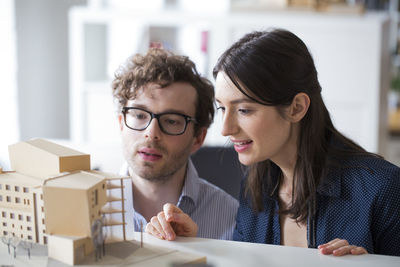 Man and woman discussing architectural model in office