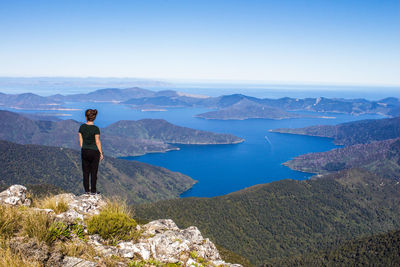 Rear view of man standing on mountain against sky