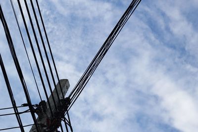 Low angle view of electricity pylon against cloudy sky