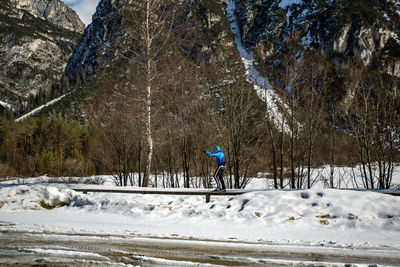 Man skiing on railing against bare trees during winter