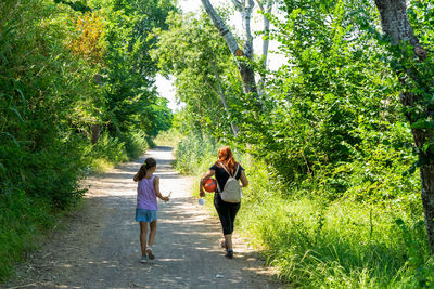 Rear view of people walking on dirt road