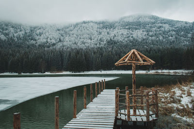 Pier on frozen lake against mountain during winter