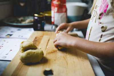 Girl preparing dough on cutting board at kitchen counter