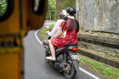 Rear view of woman riding motorcycle on road