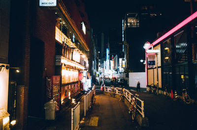 Illuminated street amidst buildings in city at night