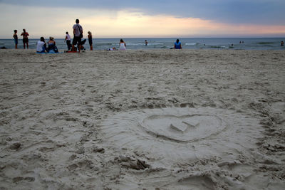 People on beach against sky during sunset