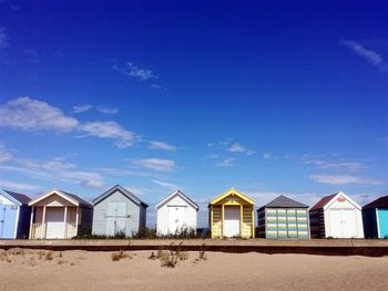 Houses on beach by buildings against blue sky