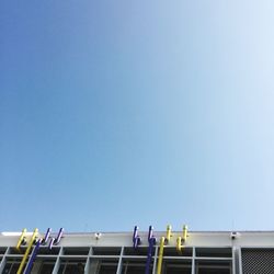 Low angle view of people against clear blue sky